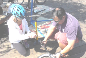 GREG ANDRADA of Wheels in Motion helps a rider inflate her tire at the bicycle clinic Aug. 2. Constance Beutel photos