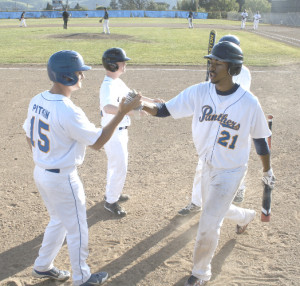 ISIAH SAGUAR (21) gets congratulated by Benicia teammate Riley Pitkin after scoring a run against Bethel. Saguar went 3-for-4 with a home run and five RBIs and also threw out a runner at first base from his centerfield position.