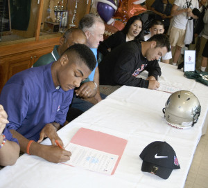 MARQUIS PERRILLIAT (left) and St. Patrick-St. Vincent High teammate Chris Stinchcomb (right) sign letters of intent to play football for Linfield College in Oregon.