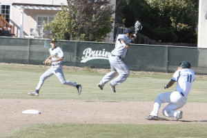 CHRIS STINCHCOMB of the Bruins (11) slides safely into second with a steal as Berean Christian shortstop Daniel Glorioso leaps for an incoming throw.