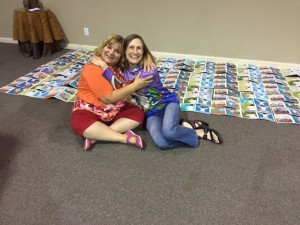 North Harbor Community Church members Susan Nuss (Left) and Susan Lucas celebrate the completion of a handmade storybook (pictured in back) about the story of Jesus and the Samaritan woman at the well from the Gospel of John. The two will take the books with them on a trip to Uganda where the books will be presented to female tribal members. (Photo courtesy of Susan Lucas)