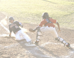 BRAEDEN CHAPMAN of Benicia slides safely into home past North catcher Vance Eschenburg during Wednesday’s opener of the District 53 Junior League Tournament.